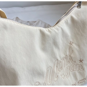 Dettaglio della borsa tote beige in nylon con ricami a stella e cerniera in metallo argento
