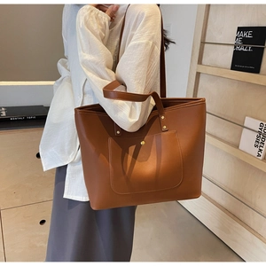 Detailed view of caramel brown tote bag with large front pocket and golden hardware buckle