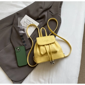Detail view of bright yellow PU leather mini backpack with drawstring and flap closure