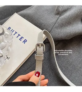 Détail de la bandoulière réglable en cuir avec boucle argentée sur sac bandoulière gris