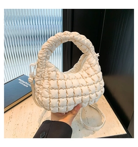 Detail of a creamy white quilted puffy handbag showing the soft texture and handle
