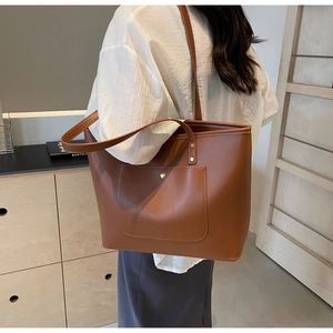 Close-up of caramel brown tote bag featuring a front pocket with metallic button detail