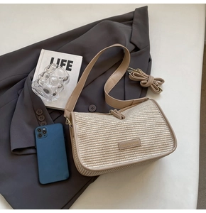 Detailed close-up of woven straw shoulder bag with leather trim on a suit jacket