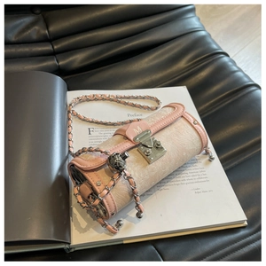Close-up of pink cylinder bag with jacquard fabric, chain strap and M-buckle detail