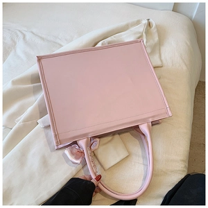 Détail du sac cabas rose montrant le cuir PU lisse et un nœud décoratif en satin chic
