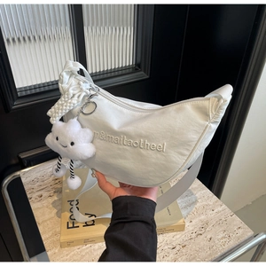 Détail du sac demi-lune en nylon blanc avec broderie et breloque nuage en peluche
