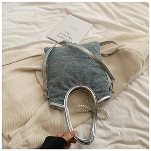 Détail du sac cabas en denim bleu avec matelassage losange, bordure argentée et perles
