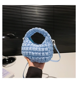 Macro detail of quilted light blue puffy nylon dumpling bag with crossbody strap