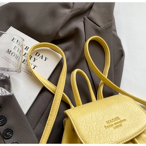 Detail of yellow pebbled leather mini backpack with debossed logo on the front flap