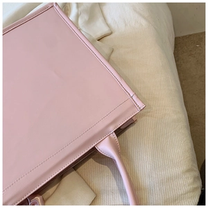 Détails des coutures et texture du cuir lisse sur un sac cabas de couleur rose