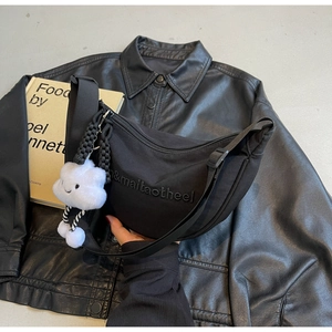 Détail du sac croissant en nylon noir avec broderie et accessoire nuage en peluche