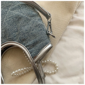 Détail du sac en denim matelassé bleu clair avec bordure argentée et chaîne perles