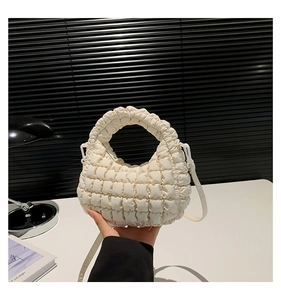 Detail of quilted nylon dumpling bag in cream white with pleated texture and thin strap
