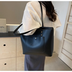 Close-up of black tote bag with large front pocket and elegant gold metal snap button