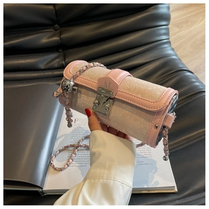 Close-up of cylinder bag with beige jacquard, pink leather trim, and silver metal ball charm