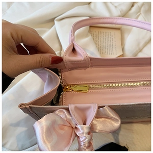 Détail du sac cabas rose avec fermeture éclair et nœud décoratif en ruban de soie