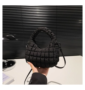 Detailed view of black quilted nylon dumpling bag with crossbody strap and top handle
