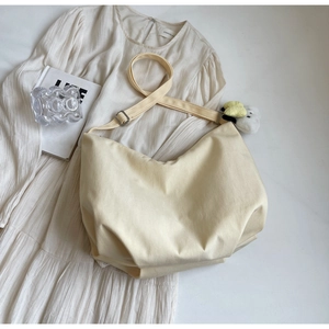 Dettaglio della borsa a mezzaluna beige in tela con ciondolo ape e tracolla regolabile