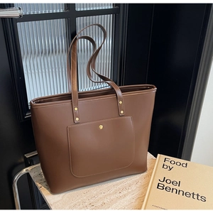 Close-up of brown matte faux leather tote bag showing the front pocket with gold magnetic buckle