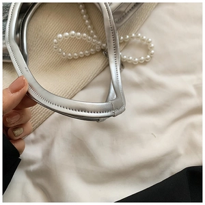 Gros plan de la poignée en cuir argenté avec chaîne de perles élégante sur le sac