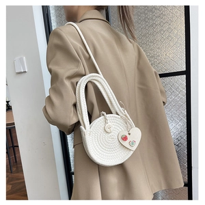 Close-up of a white woven round bag featuring a strawberry heart charm and a spiral texture