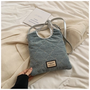 Détail du sac en jean bleu avec motif matelassé en strass et poignées argentées