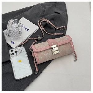 Macro detail of a pink cylindrical crossbody bag with silver M lock and chain strap
