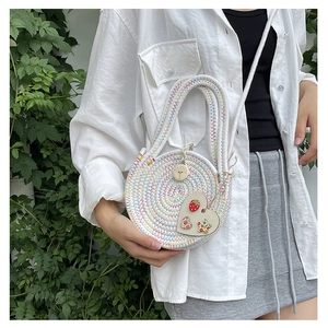Close-up of a white woven round bag featuring colorful stitching and a heart-shaped charm