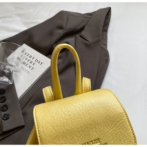 Detail of yellow pebbled leather mini backpack with embossed logo and handle