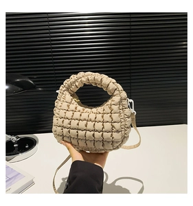 Detail of beige quilted puffer dumpling bag showing soft fabric texture and crossbody strap