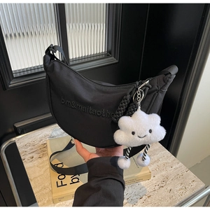 Détail du sac bandoulière demi-lune noir en nylon avec logo brodé et charme peluche