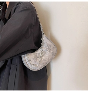 Détail du tissu jacquard floral gris clair et chaîne fleurie argentée sur le sac