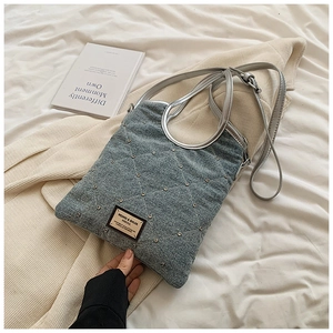 Détail du sac en denim bleu avec rivets brillants et poignée anneau argentée élégante