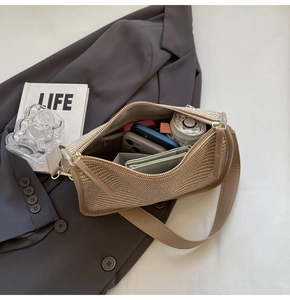 Detail view of woven shoulder bag showing spacious interior with zipper pocket and daily items
