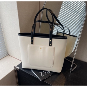 Detail of minimalist tote bag showing gold buckle and contrast black leather trim