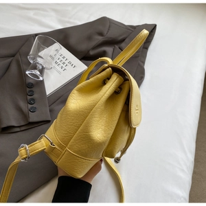 Detail of a bright yellow bucket backpack in lychee texture leather with drawstring