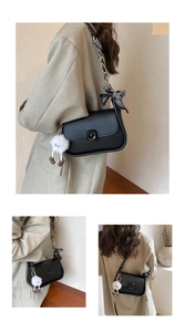 Detail of black crossbody bag with gold chain strap, silk scarf and plush doll charm