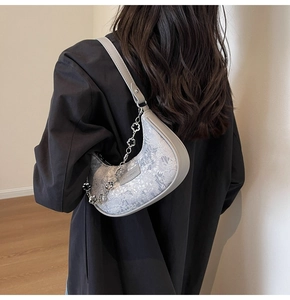 Détail du sac croissant en jacquard gris avec chaîne métallique florale et étiquette