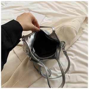 Vue détaillée de l'intérieur du sac argenté avec doublure marron, poche zippée et perle