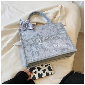 Vue détaillée du sac cabas en toile brodée bleue avec foulard en soie et logo