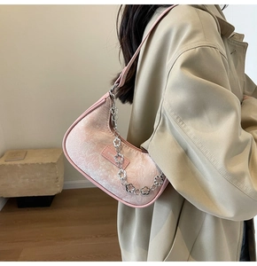 Détail du sac jacquard rose avec chaîne florale argentée décorative et bandoulière en cuir