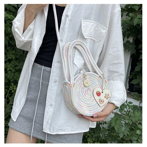 Close-up of circular straw bag with colorful spiral stitching and heart wooden charm