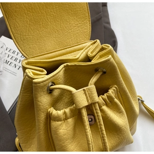 Close-up of yellow lychee-patterned leather backpack with drawstring closure and flap