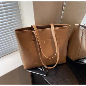 Detail of a brown PU leather tote bag featuring a front pocket and golden snap button