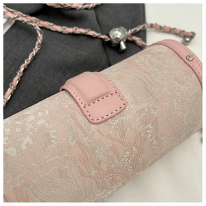 Detail of pink cylindrical bag featuring intricate floral textures and silver chain strap
