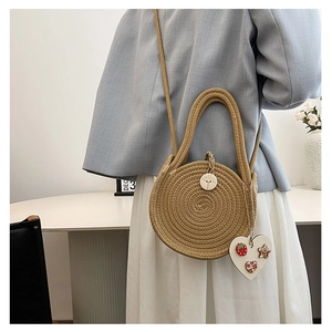 Detail of round straw beach bag with circular weave and heart-shaped floral embroidery