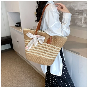 Detail of woven straw tote bag with cream stripes, lace bow and floral accents