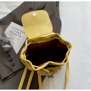 Bright yellow pebbled leather mini backpack with burgundy lining and drawstring closure
