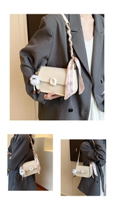 Detail of off-white leather crossbody bag with square buckle and fuzzy monster charm