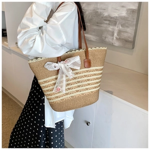 Detailed macro view of straw tote with white lace bow and delicate rose embroidery